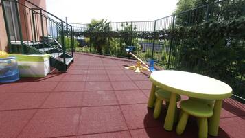 Relax on the patio with a table and chairs, surrounded by lush greenery and a staircase leading to the upper level.