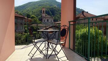 Un balcone con tavolo e sedie, vista su una chiesa collinare e edifici circostanti.