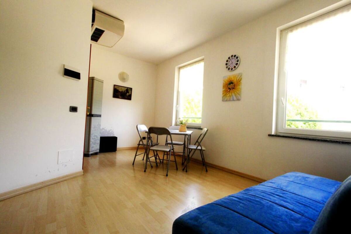Ein Zimmer mit einem Bett, einem Tisch mit Stühlen, einem Fenster und einer Wanduhr.