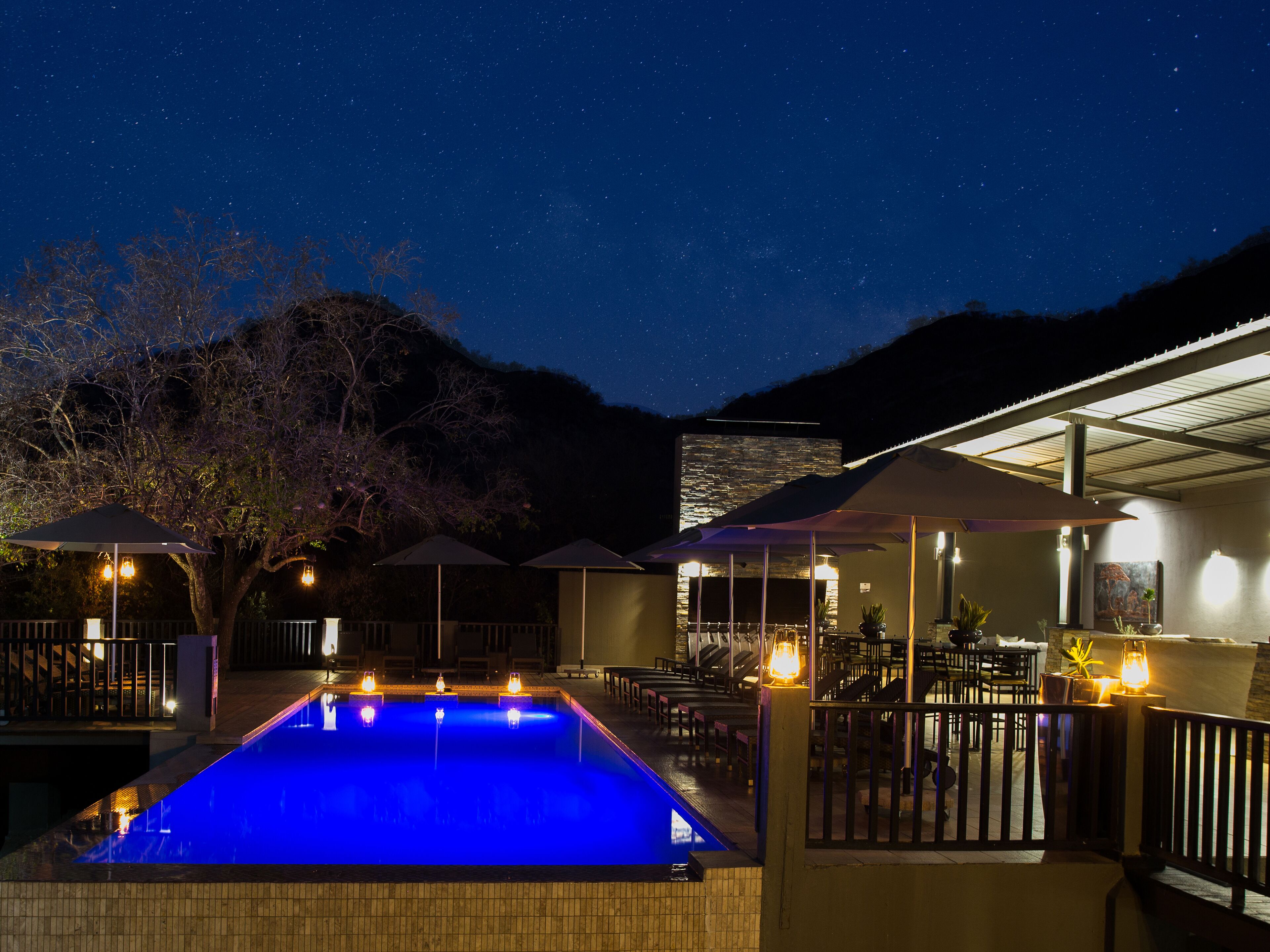Una piscina al aire libre, sombrillas, sillones reclinables de piscina