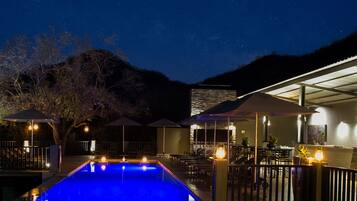 Una piscina al aire libre, sombrillas, sillones reclinables de piscina