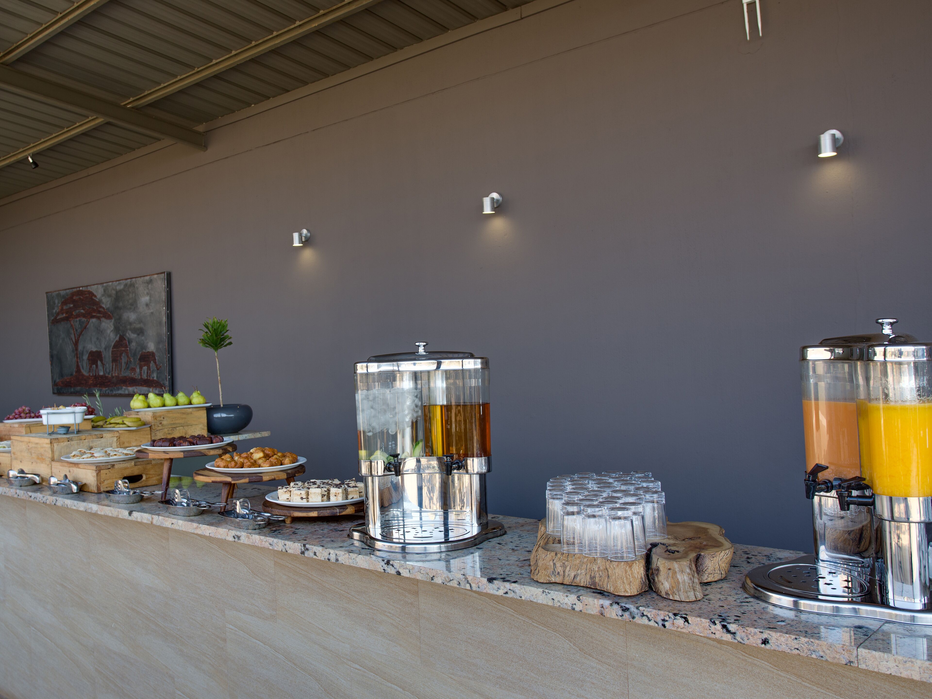 A buffet setup with various food items and beverages, including a coffee station and a fruit display.
