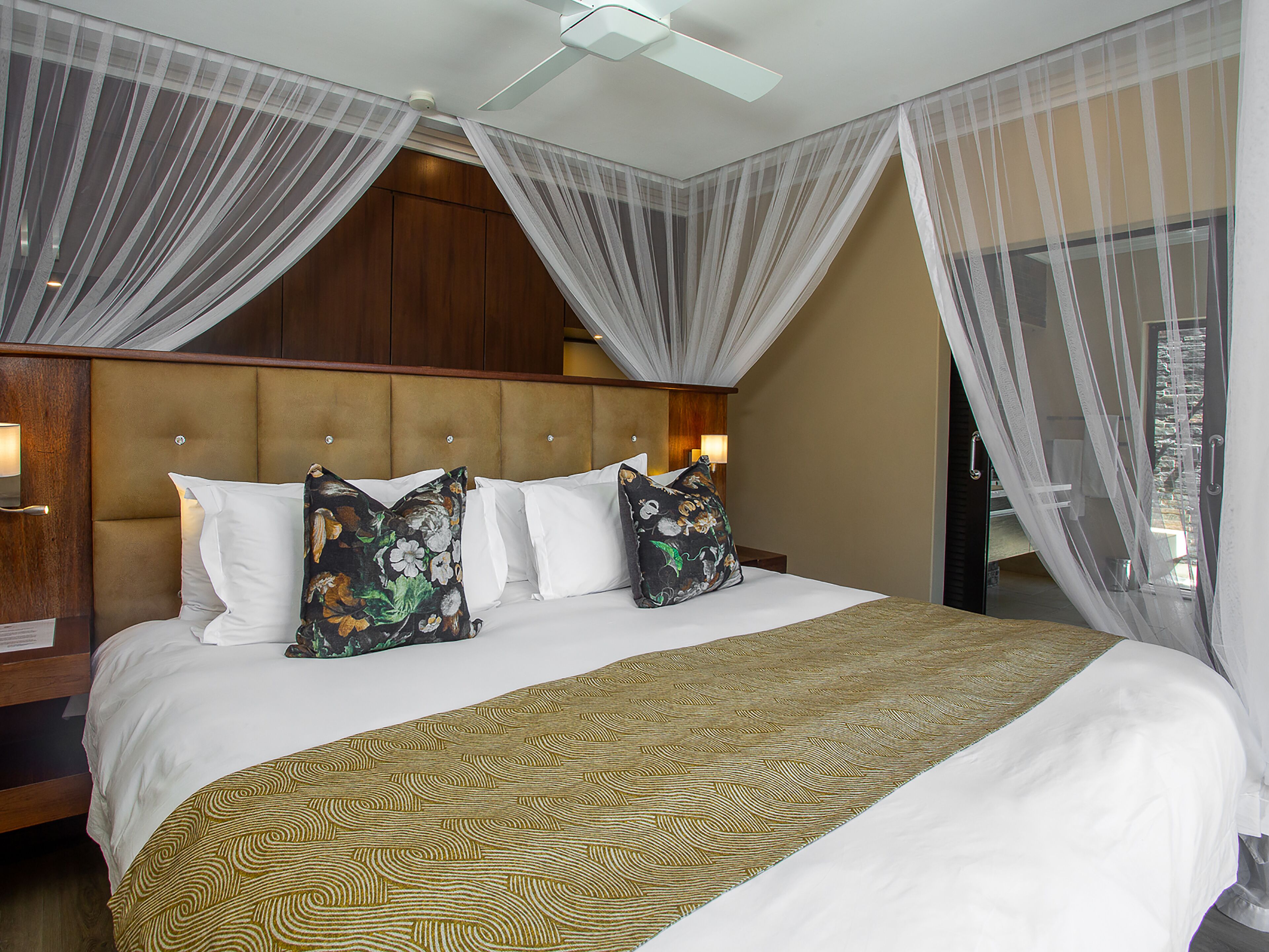 Een hotelkamer met een groot bed, een hoofdeinde en transparante gordijnen.