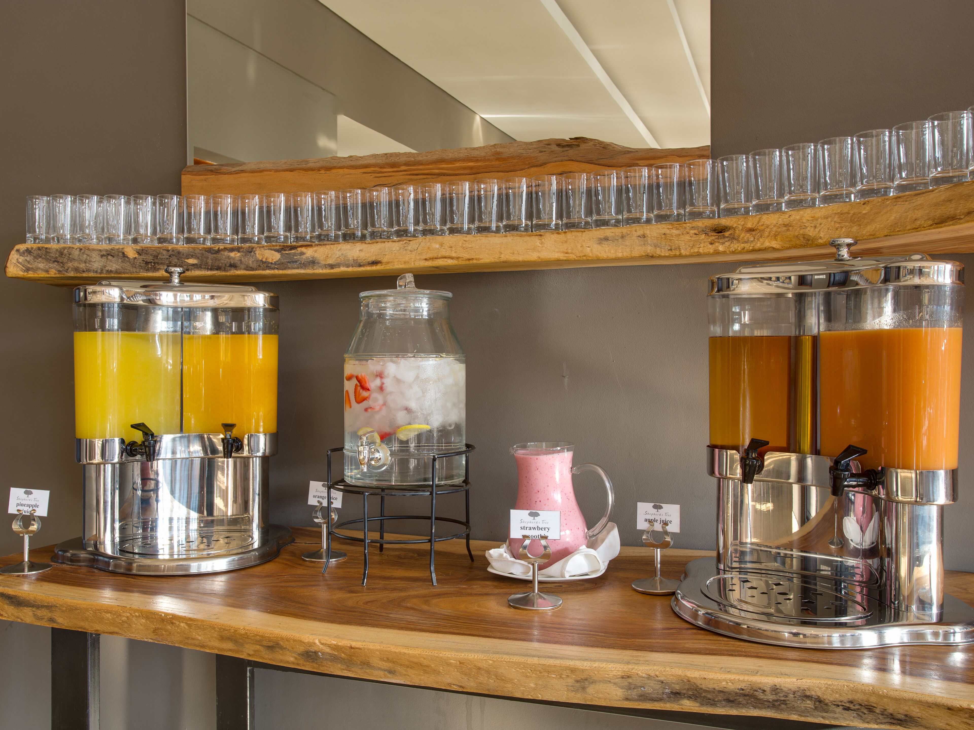 Een drankstation met verschillende tappunten, waaronder een karaf met een bloemmotief en een glazen karaf met een roze drank.