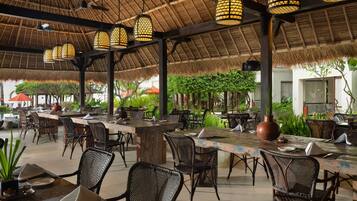 An outdoor dining area with thatched roofs, wicker furniture, and hanging lanterns.