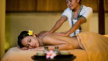 A person receiving a massage in a room with a wooden ceiling and a massage table.