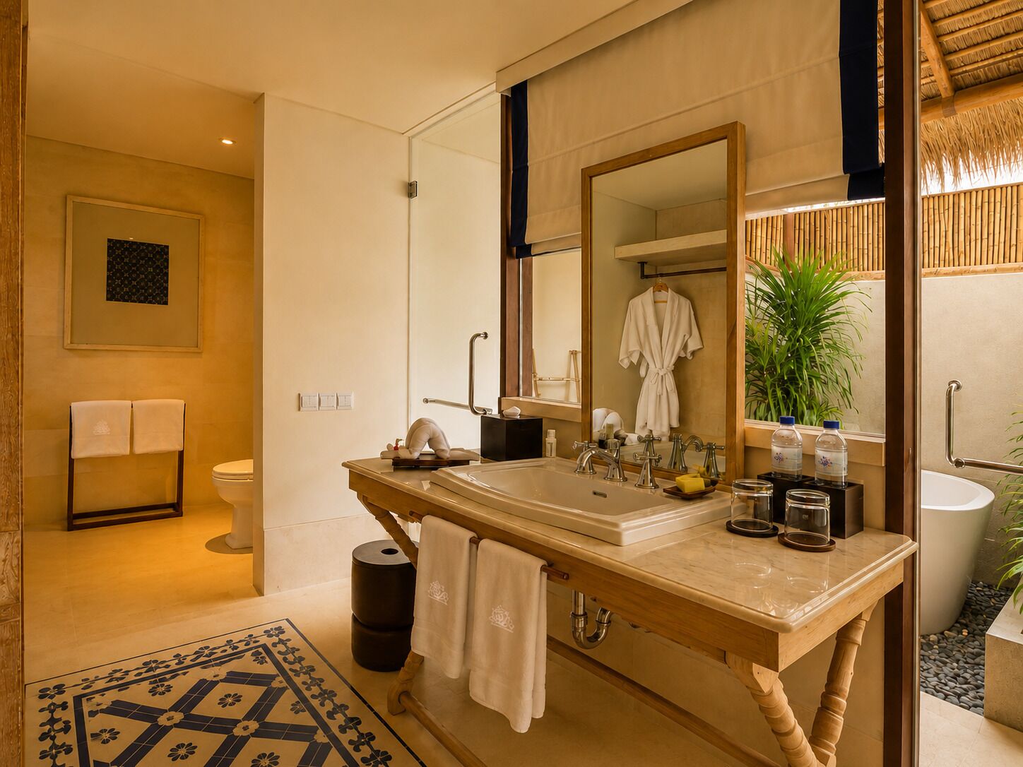 A bathroom with a large mirror, a sink with multiple faucets, a towel rack, and a toilet.