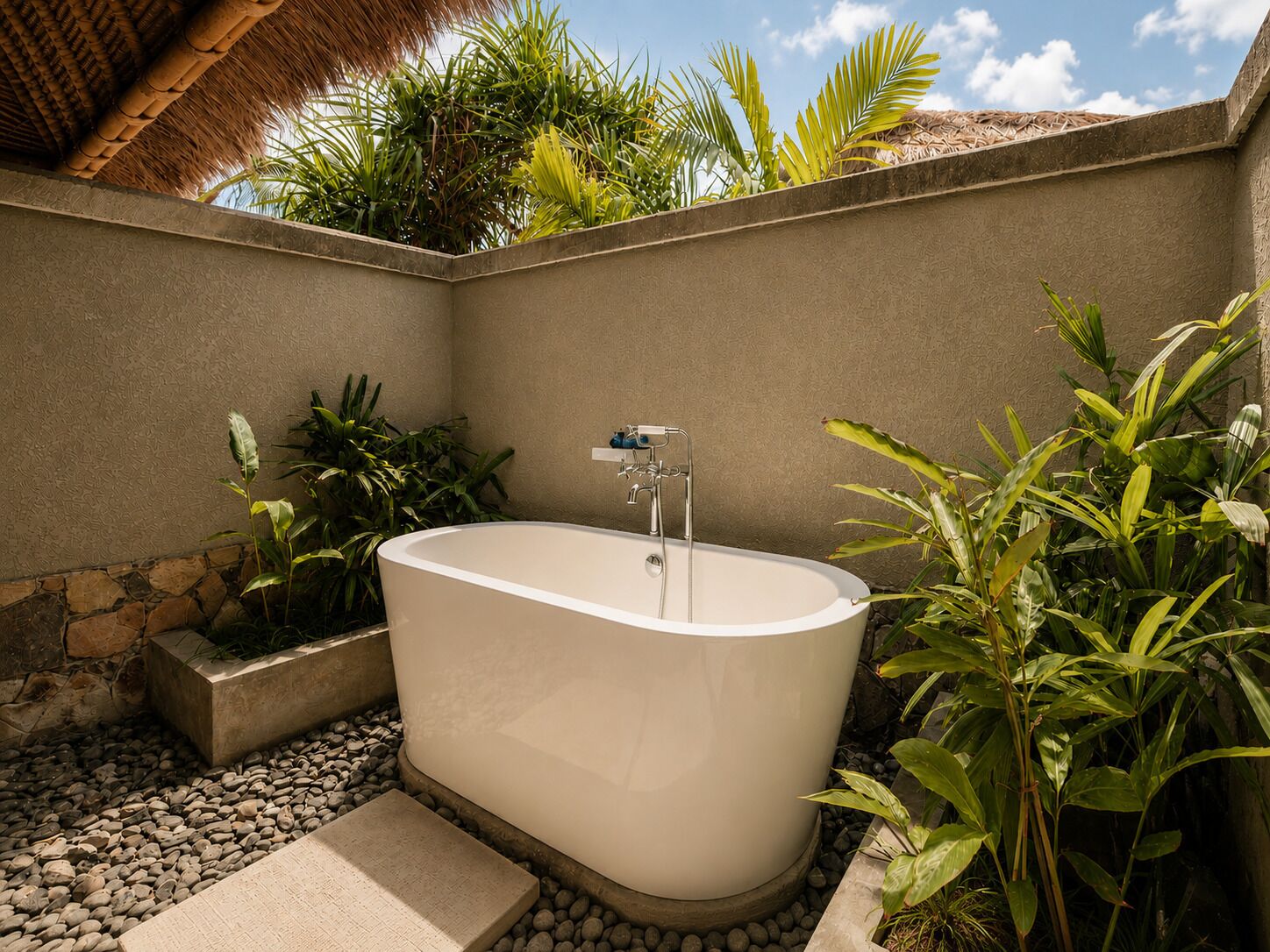 Une baignoire sur pied, installée dans un jardin, avec un mur en pierre et des plantes tropicales.