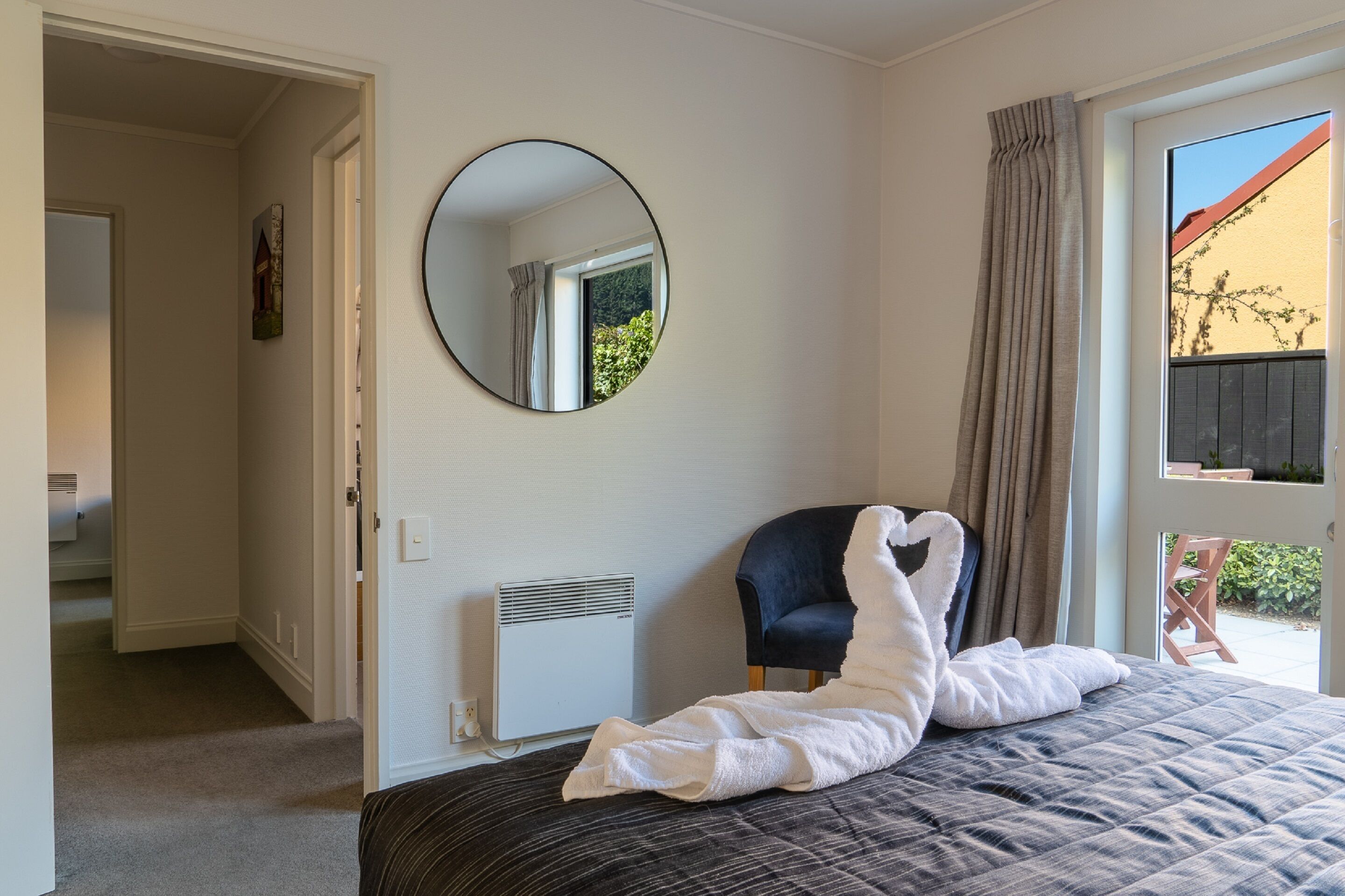 Een slaapkamer met een bed, een stoel, een verwarming, een spiegel en uitzicht op de omgeving.