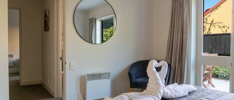 Een slaapkamer met een bed, een stoel, een verwarming, een spiegel en uitzicht op de omgeving.