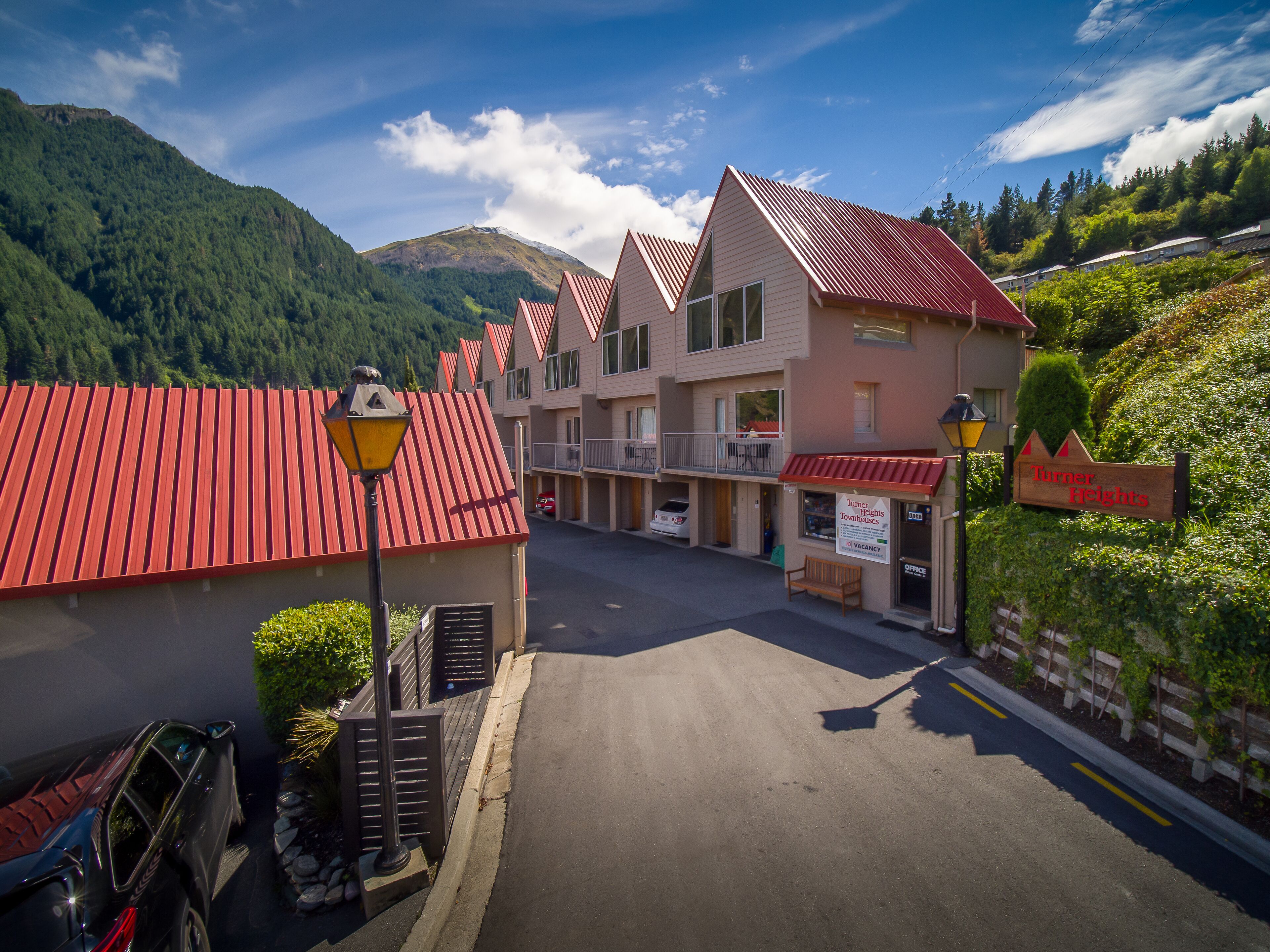 Un hotel con techo rojo, un letrero que dice "Turner Heights" y vistas de montañas al fondo.