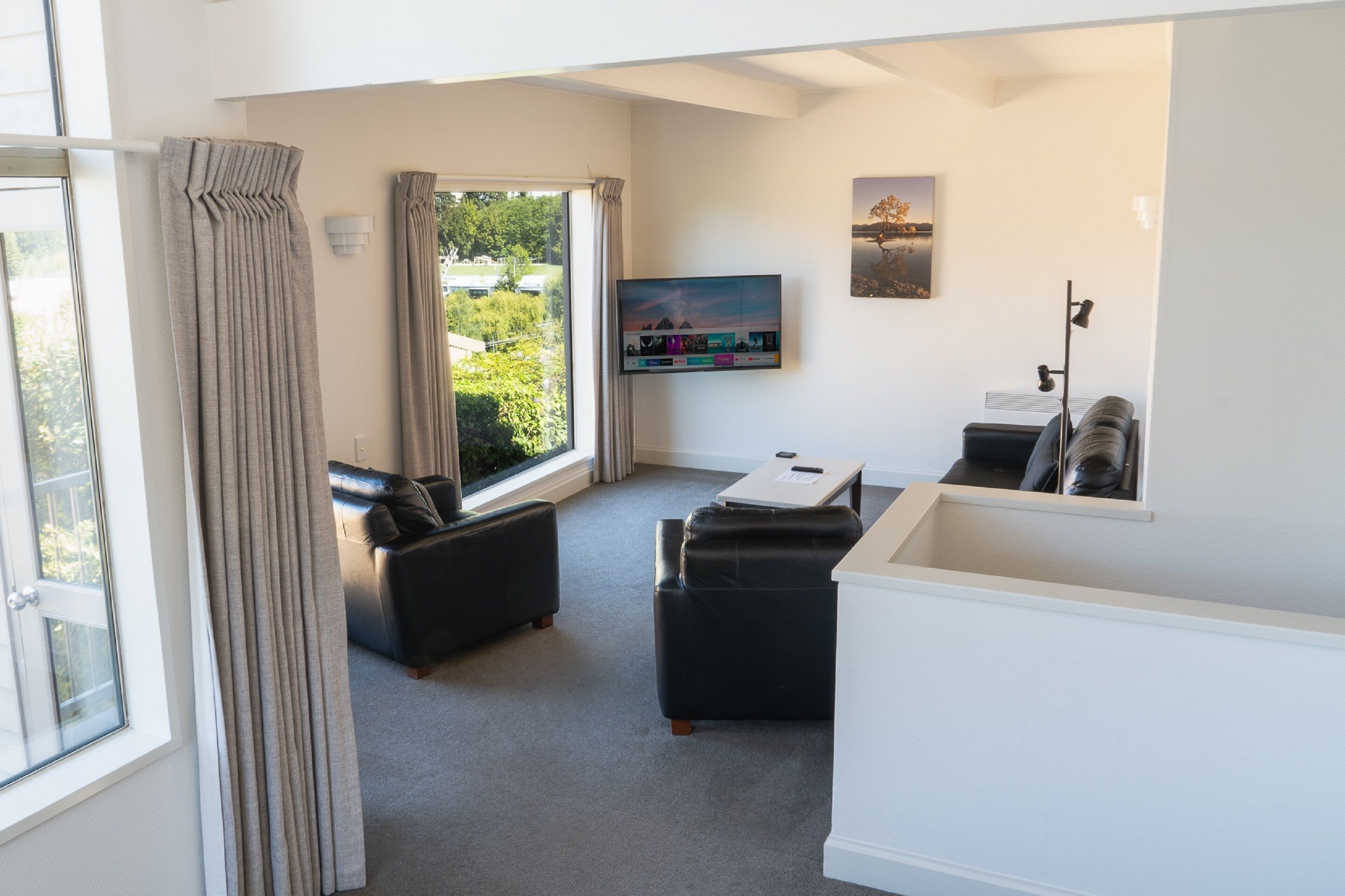 A modern living room with a sofa, a coffee table, and a TV mounted on the wall.