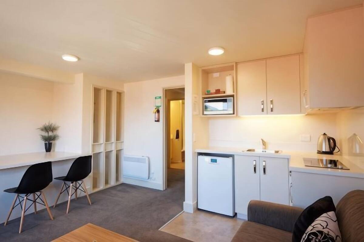A compact living space with a kitchenette, a dining area with chairs, and a sofa.