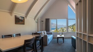 Quarto moderno com área de refeições, sofá e grande janela com vista para as montanhas.