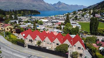 Un pueblo costero con casas de tejados rojos, una carretera y montañas al fondo.