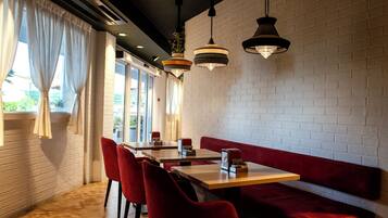 Ein Restaurantinneres mit Backsteinwänden, roten Sitzgelegenheiten und Pendelleuchten.