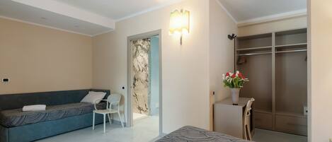 Una habitación de hotel con cama, sofá, silla, escritorio, armario y baño.