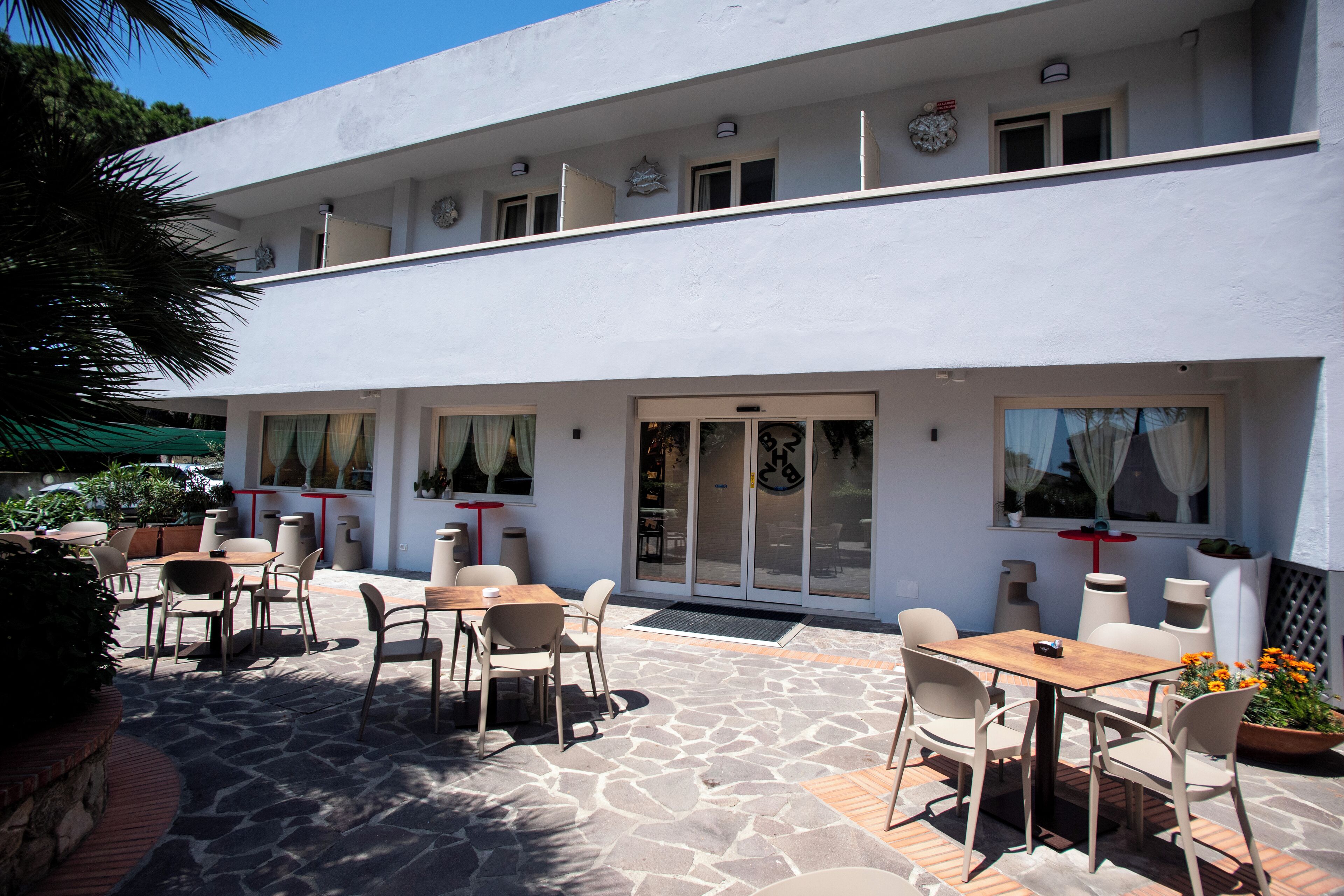 Ein Gebäude mit einer Terrasse, Sitzgelegenheiten im Freien und einem Steinfußboden.