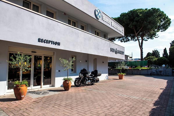 Una reception di hotel con insegna bed and breakfast, una motocicletta parcheggiata fuori e piante in vaso.