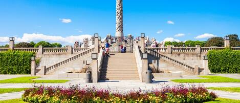 A monument with a staircase leading up to it, surrounded by a landscaped garden with colorful flowers.