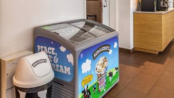 A reception area with a Ben & Jerry's ice cream machine, a trash can, and a sign indicating no smoking in the area.