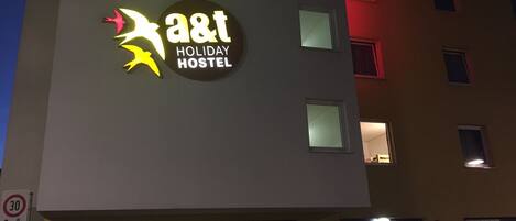 En bygning med et skilt, der viser 'a&t Holiday Hostel'.