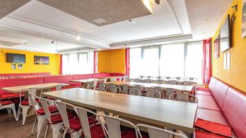 Un'area ristorazione con banconi e tavoli, pareti giallo brillante e tocchi di rosso.