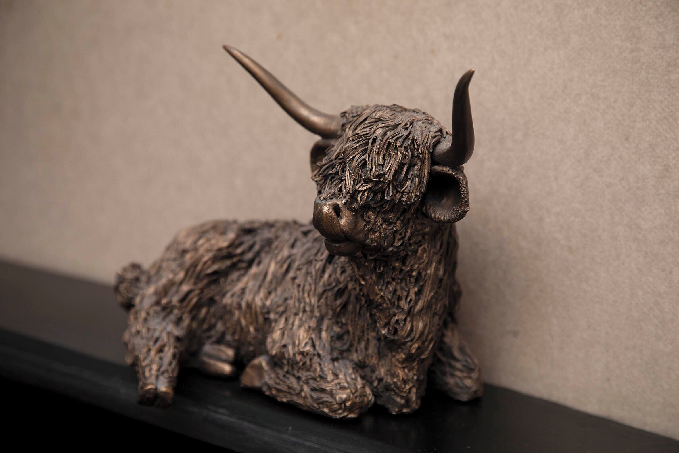 A bronze bull sculpture on a shelf against a plain wall.