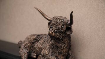 A bronze bull sculpture on a shelf against a plain wall.