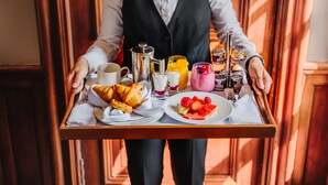 A tray with breakfast items including croissants, fruit, and beverages.
