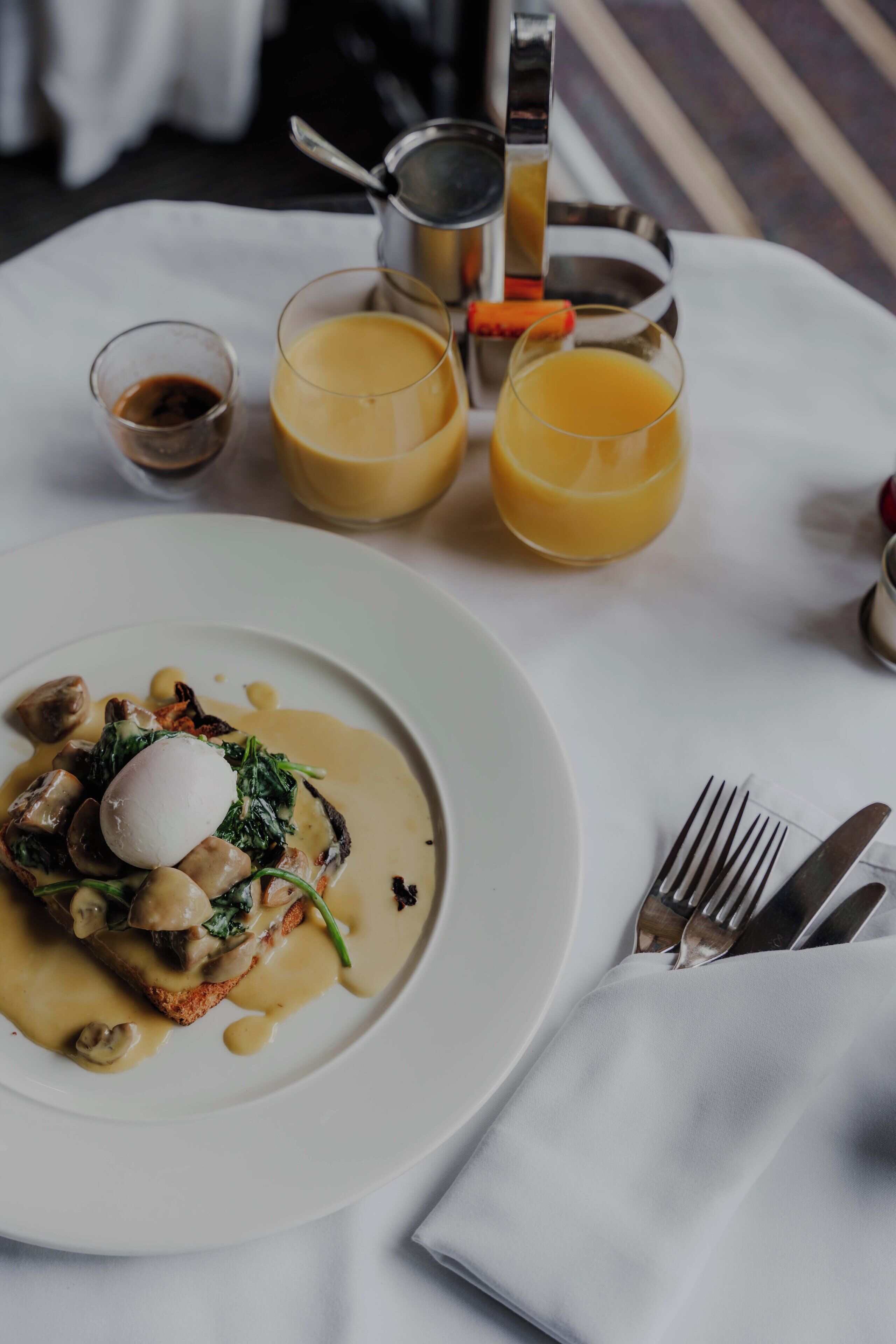 A breakfast setting with a plate of food, two glasses of orange juice, and a pitcher of coffee.