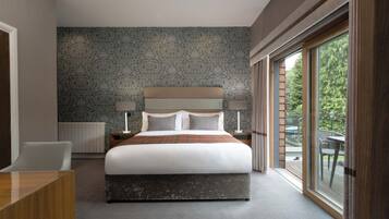 Une chambre d’hôtel moderne, dotée d’un grand lit, d’un bureau et offrant une vue sur l’extérieur grâce à une porte-fenêtre coulissante.