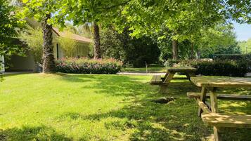 A well-maintained garden with a picnic table and a building with a red-tiled roof.
