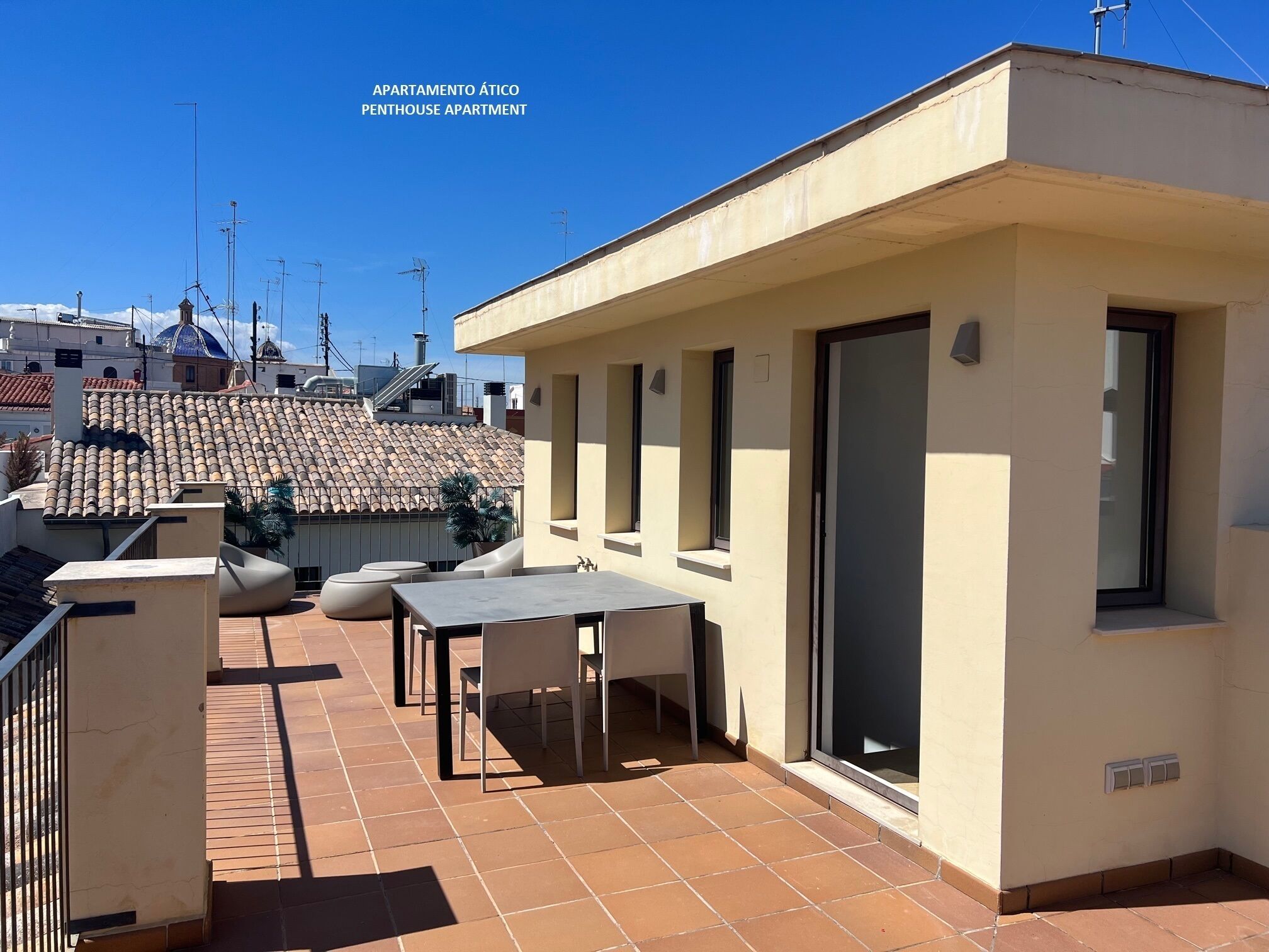 Un apartamento tipo ático con terraza, una mesa y sillas.