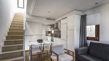 Une cuisine moderne avec des meubles blancs, un coin repas comprenant une table et des chaises, et un escalier.