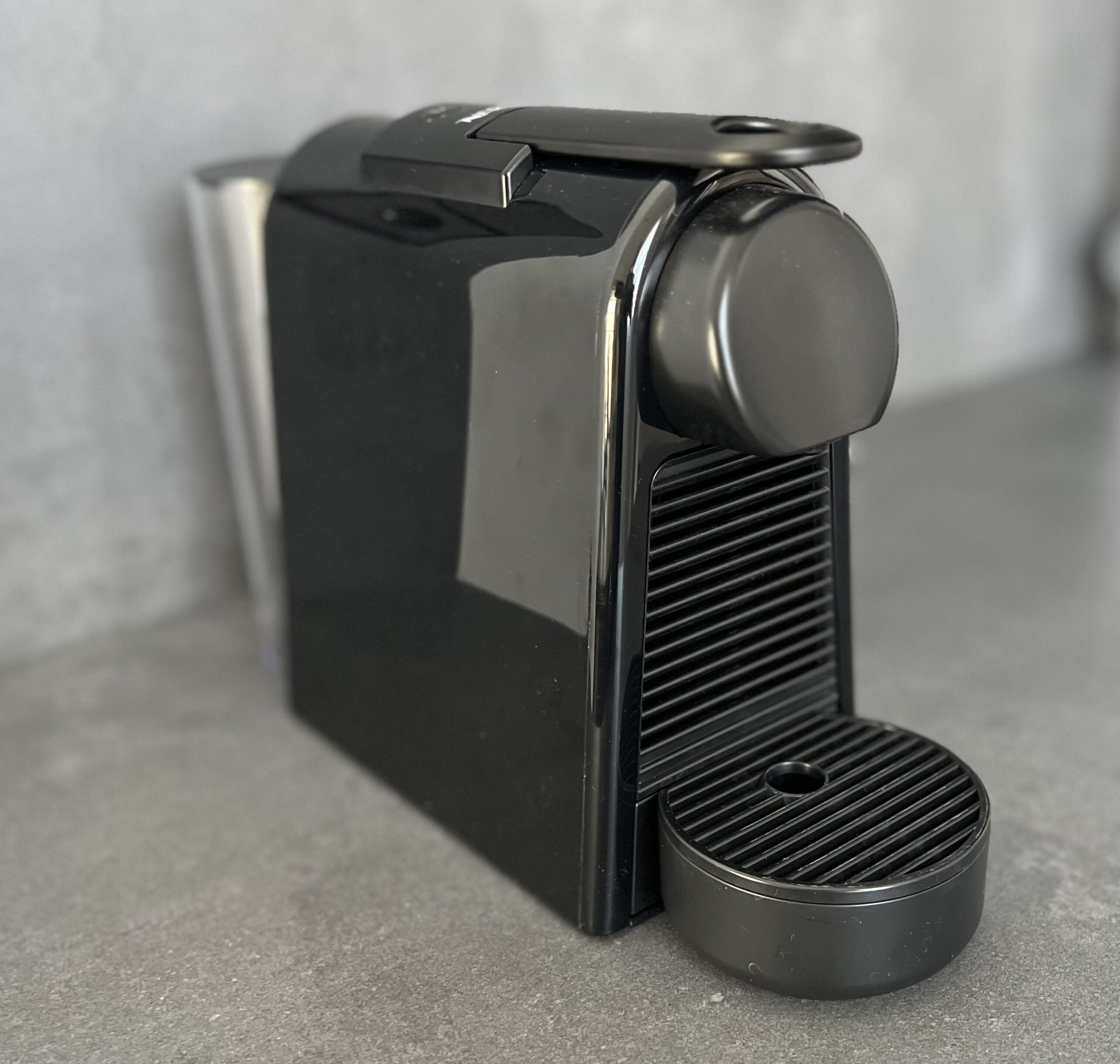 A black espresso machine with a single coffee portafilter and a drip tray.