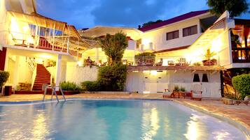 Relax by the pool surrounded by a two-story building with a balcony overlooking the area.