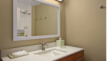 A bathroom with a large mirror, a sink, a towel rack, and a toilet.