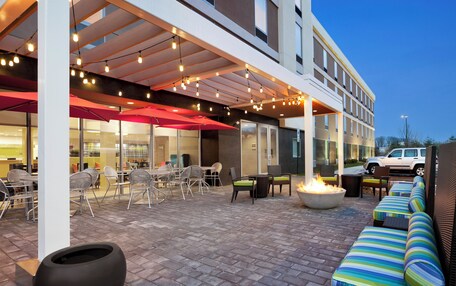 An outdoor patio area with seating, a fire pit, and string lights.