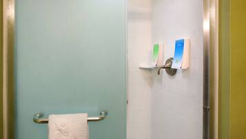 Un baño con toallero, ducha y estante con artículos de aseo.