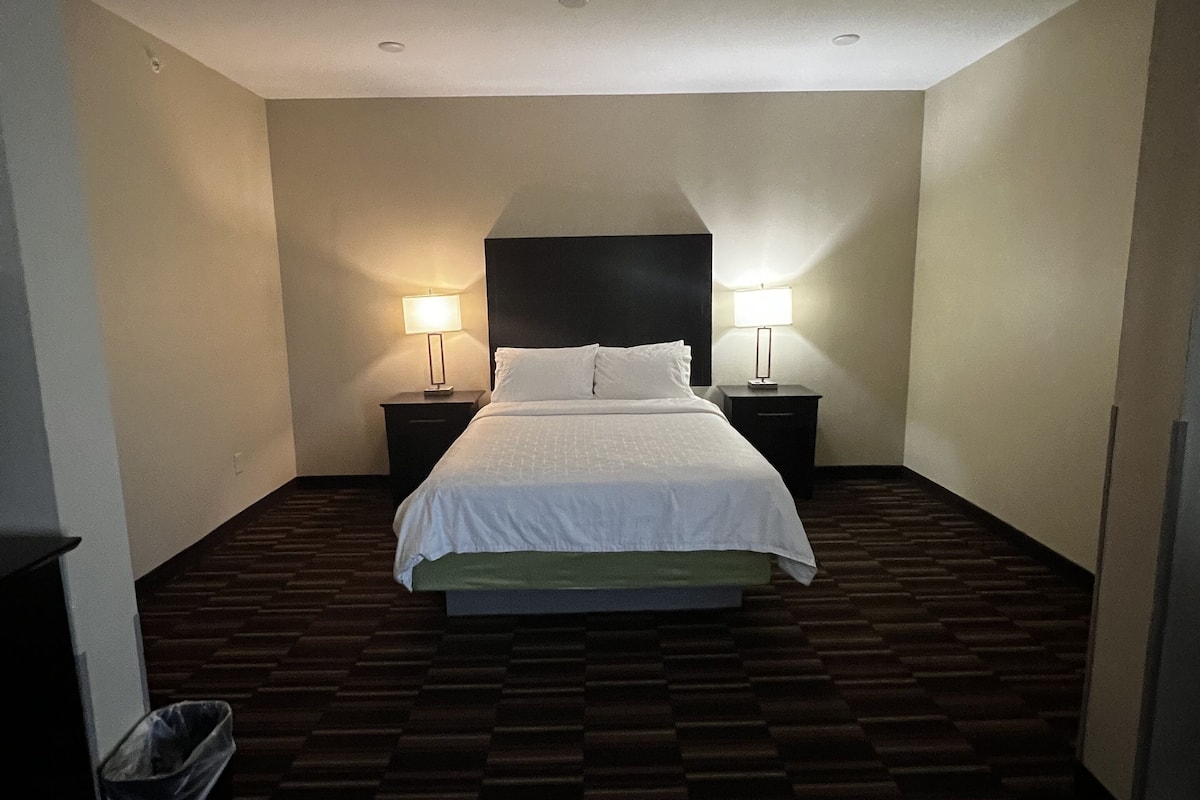 A hotel room with a large bed, two bedside tables, and a headboard.