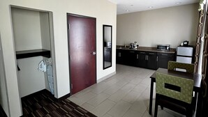 A hotel room with a kitchenette, a dining area with a table and chairs, and a patterned carpet. - Holiday Inn Express Hotel & Suites Alva by IHG (Alva)