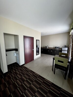Une chambre d’hôtel dotée d’une kitchenette, d’un coin repas avec une table et des chaises, et d’un tapis à motifs.