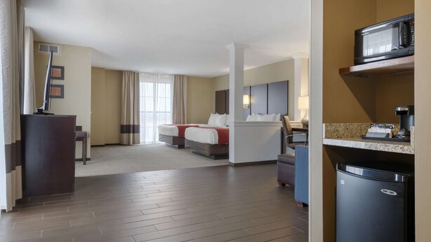 Een hotelkamer met een bed, een bureau, een magnetron en een koelkast.