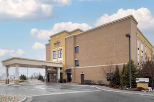 Un hotel Comfort Suites junto a una gasolinera, con estacionamiento techado y un cartel que anuncia el Worthington Event Center.