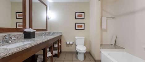 A bathroom with a marble sink, a toilet, a bathtub, and framed pictures on the wall.