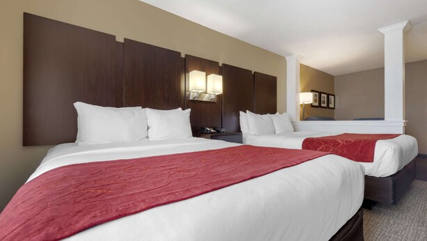 A hotel room with two beds, a large mirror, and a nightstand with a lamp. - Comfort Suites and Conference Center (Worthington)