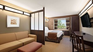 Una habitación de hotel con cama, sofá, escritorio y televisión.