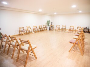 A room with wooden chairs arranged in a circle, a small table, and a potted plant.