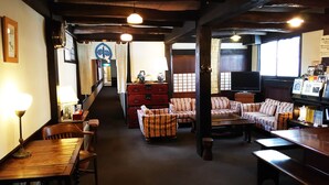 A traditional inn with wooden furniture, a TV, and a staircase leading to the upper floor. - Rickshaw Inn (Takayama)